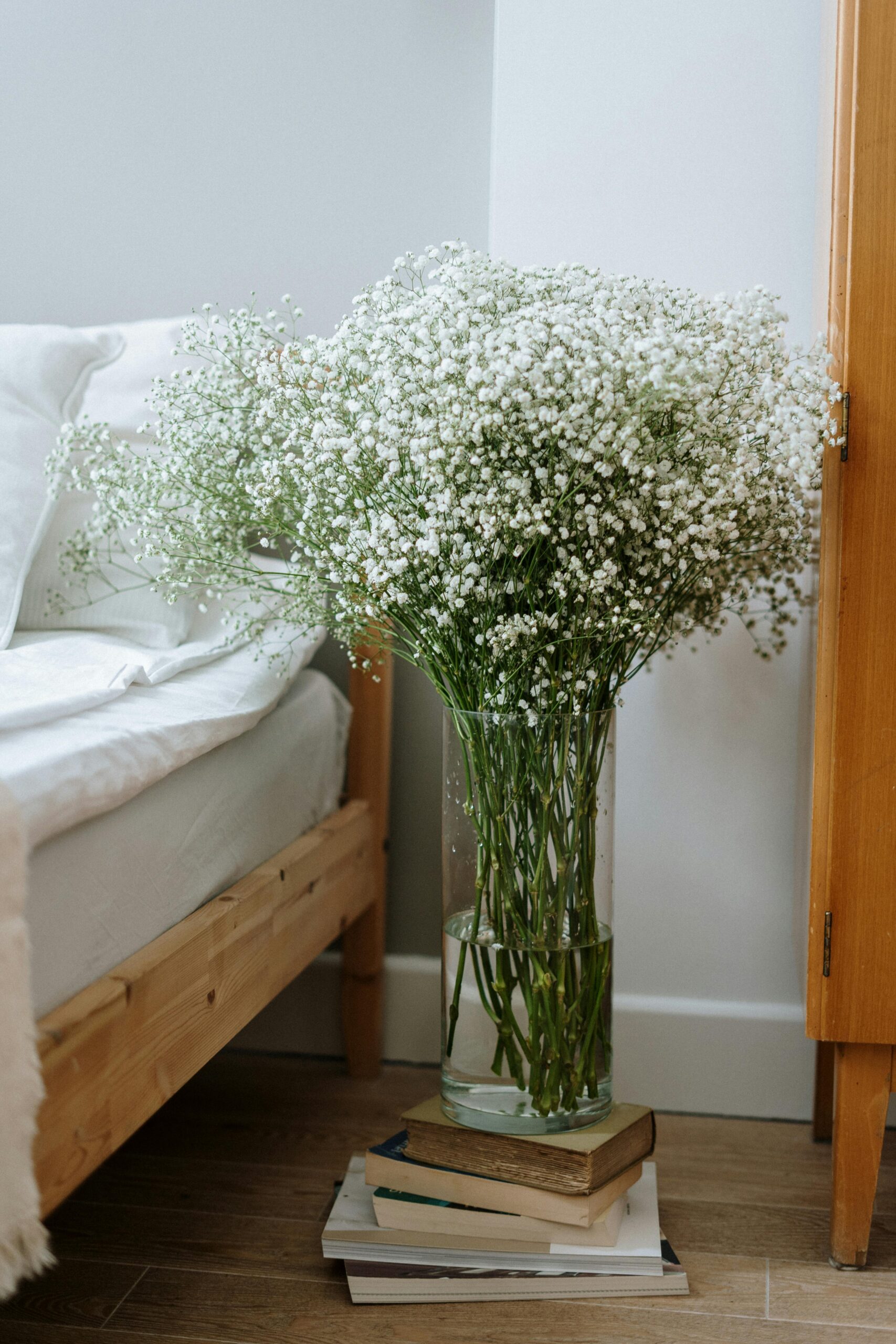A calming bedroom corner with a large vase of white baby’s breath flowers beside a neatly made bed, evoking a fresh, cared-for North Vancouver home.