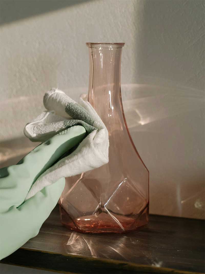 A gloved hand gently polishing a glass vase, showcasing Lenuma’s careful, detail-oriented approach to home cleaning.