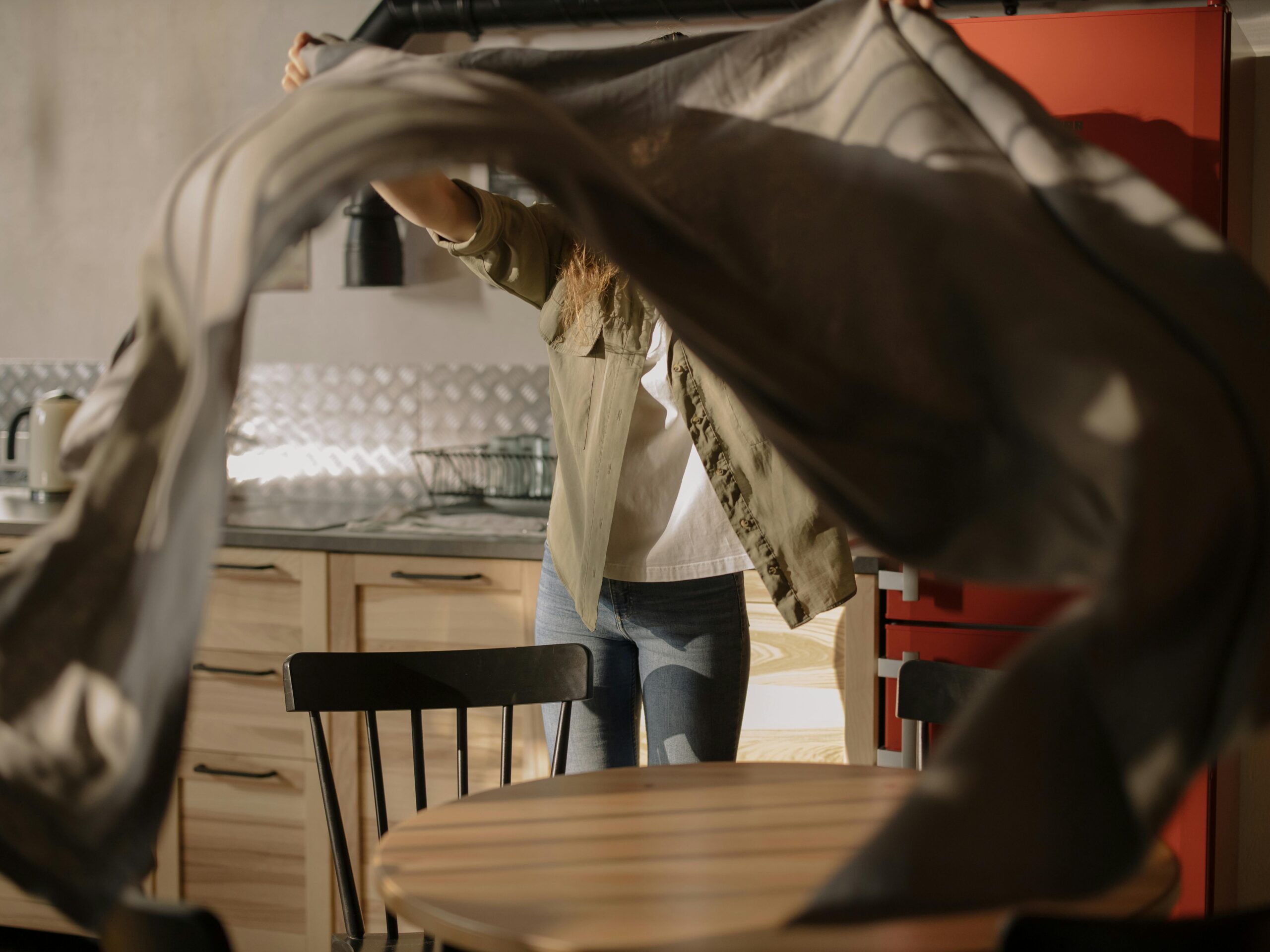 A home care professional shakes out a cloth in a cozy North Vancouver kitchen, preparing the space for a thorough, eco-friendly clean.